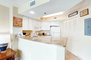 A kitchen with white cabinets, a granite countertop, a microwave, a stove, and a refrigerator. - Carolinian Beach Resort 1735 (Myrtle Beach)