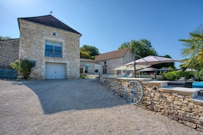 A stone building with a garage, outdoor seating, and a wheelbarrow.