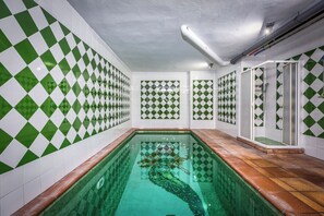 A swimming pool with a checkered tile pattern on the walls and a clear glass bottom.