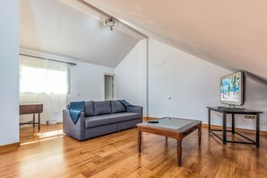 A modern living room with a grey sofa, a glass coffee table, and a painting on the wall.
