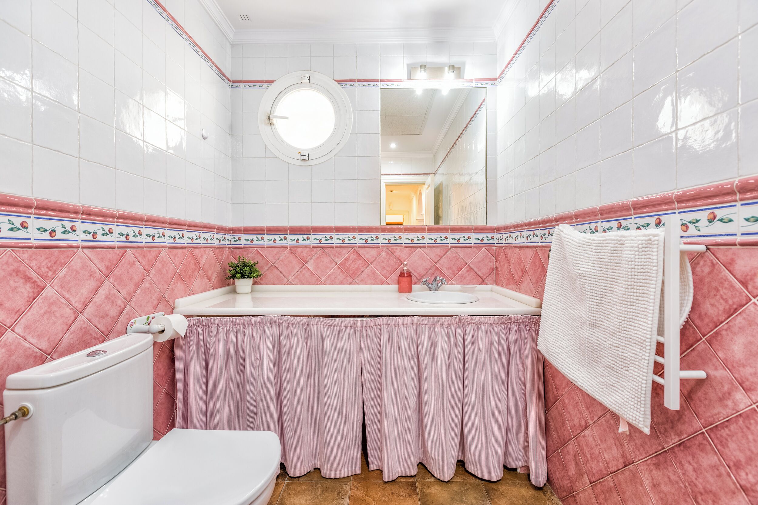 A bathroom with a toilet, sink, and mirror.