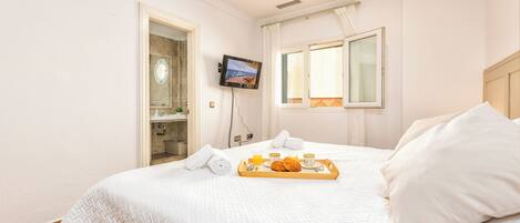 A hotel room with a bed, a TV, a window, and a breakfast tray.