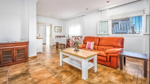 Ein Wohnzimmer mit einem Holztisch, einem Ledersofa und einem Essbereich mit weißem Tischlein.