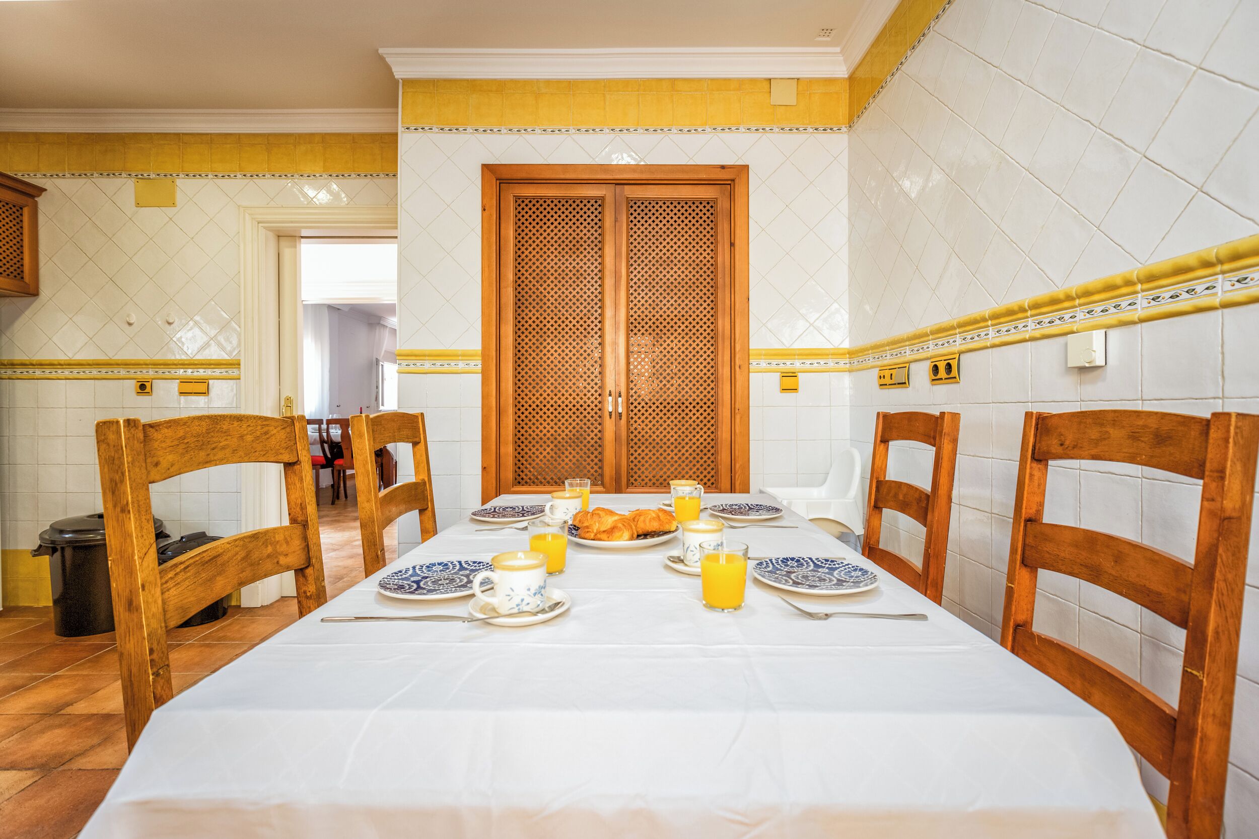A dining area with a table set for breakfast, including plates, cups, and a croissant.