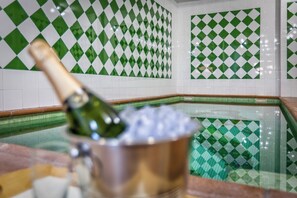 A bottle of champagne in a metal bucket on a counter with a green and white checkered tile backsplash.