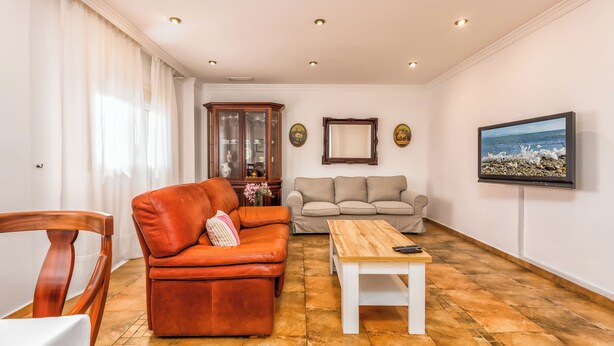 Ein Wohnzimmer mit einem braunen Ledersofa, einem weißen Couchtisch, einem beigefarbenen Sofa und einem Holzkabinett.