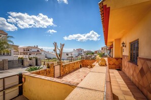 A residential area with a paved patio, stone walls, and a clear blue sky.