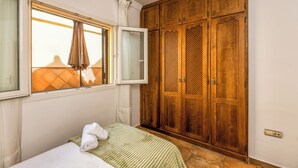 Ein Schlafzimmer mit einem Bett, einem Fenster mit Vorhängen und einem Holzschrank.