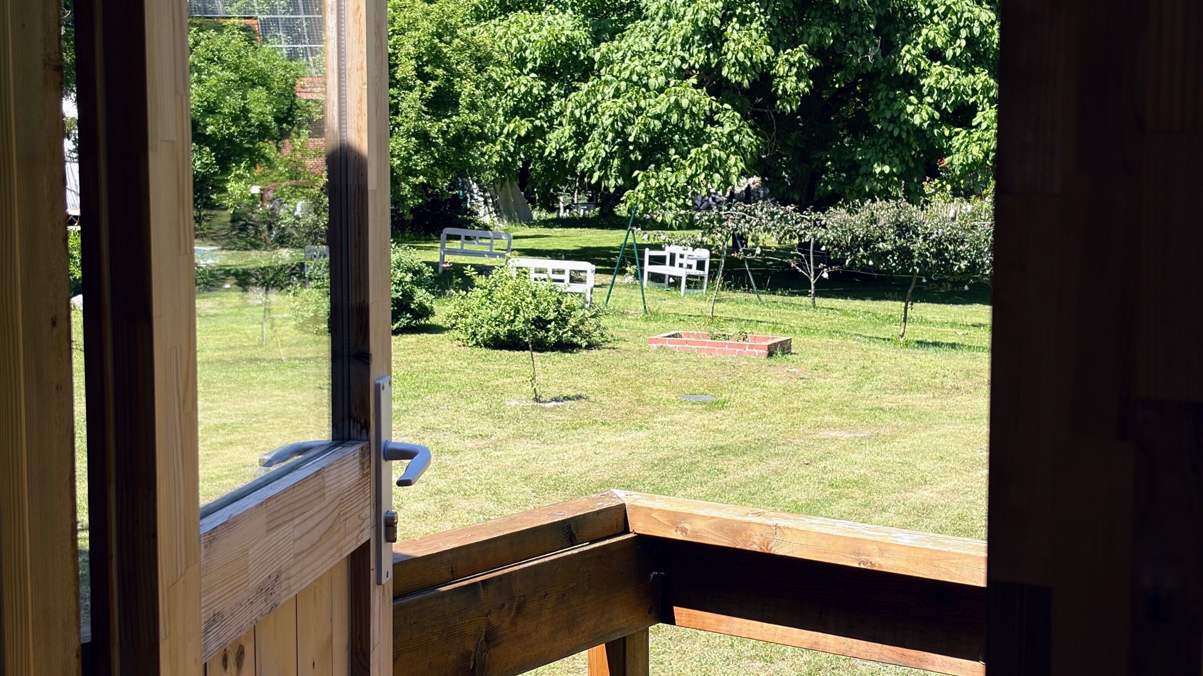 Eine Holzterrasse mit Blick auf einen Rasen und ein Backsteinhaus.