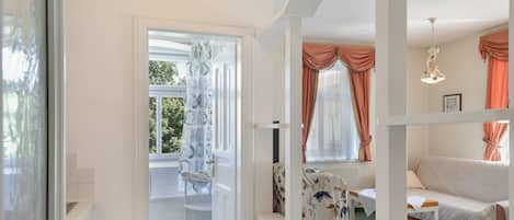 Una habitación con cama, una silla, una mesa y un ventanal con cortinas.