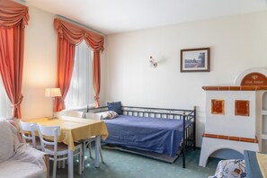 A room with a bed, a table, chairs, a lamp, a painting, and a fireplace. - Apartment Grattschlössl 3 with mountain view, balcony and Wi-Fi (Sankt Johann)