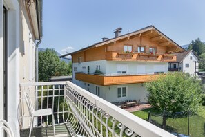 A two-story wooden house with a balcony, a small garden, and a mountain in the background. - Apartment Grattschlössl 3 with mountain view, balcony and Wi-Fi (Sankt Johann)