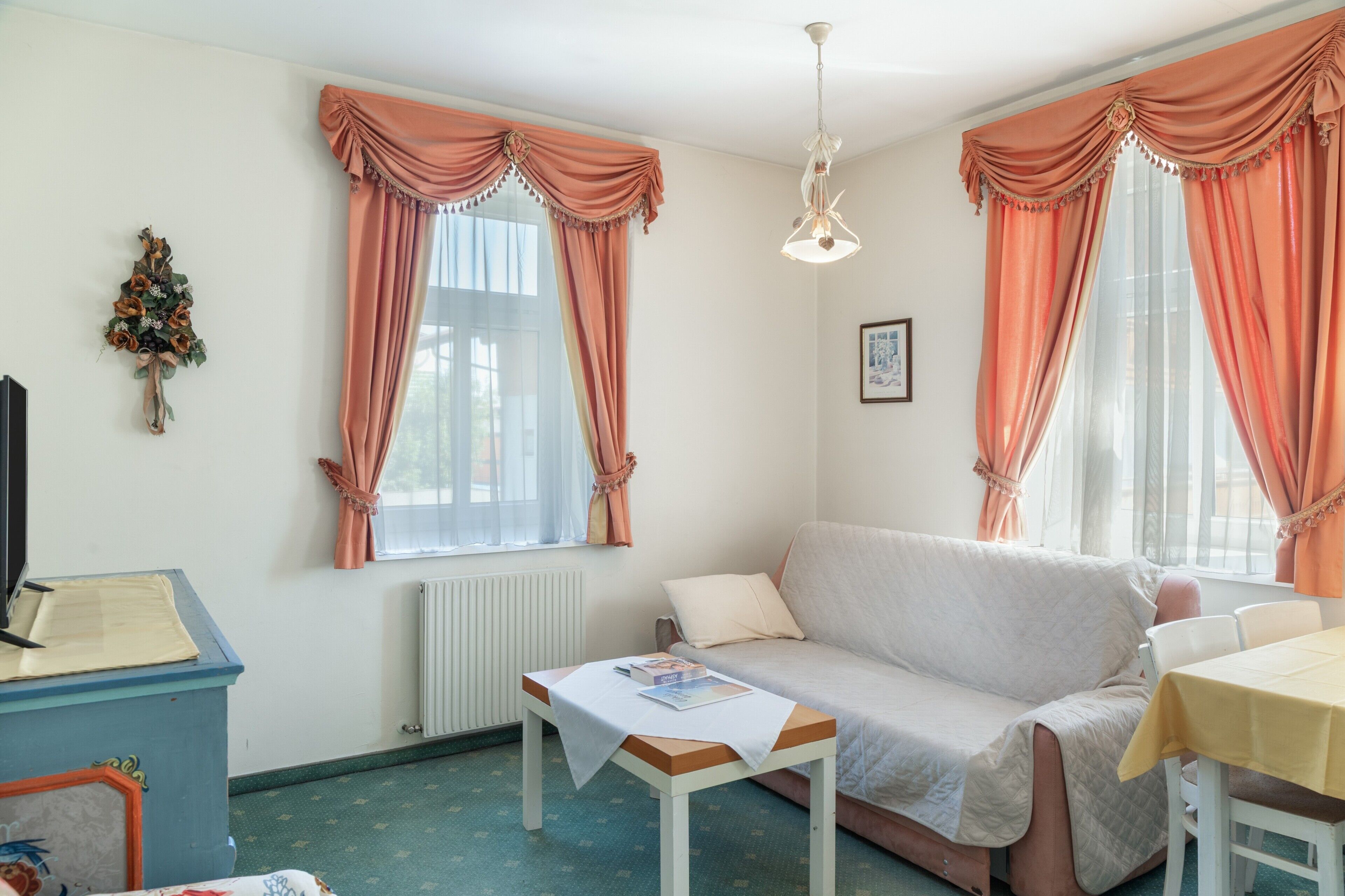 Une pièce confortable avec un canapé, une table et deux fenêtres avec des rideaux.