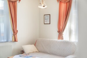 A cozy room with a sofa, a table with a book, and a framed picture on the wall. - Apartment Grattschlössl 3 with mountain view, balcony and Wi-Fi (Sankt Johann)