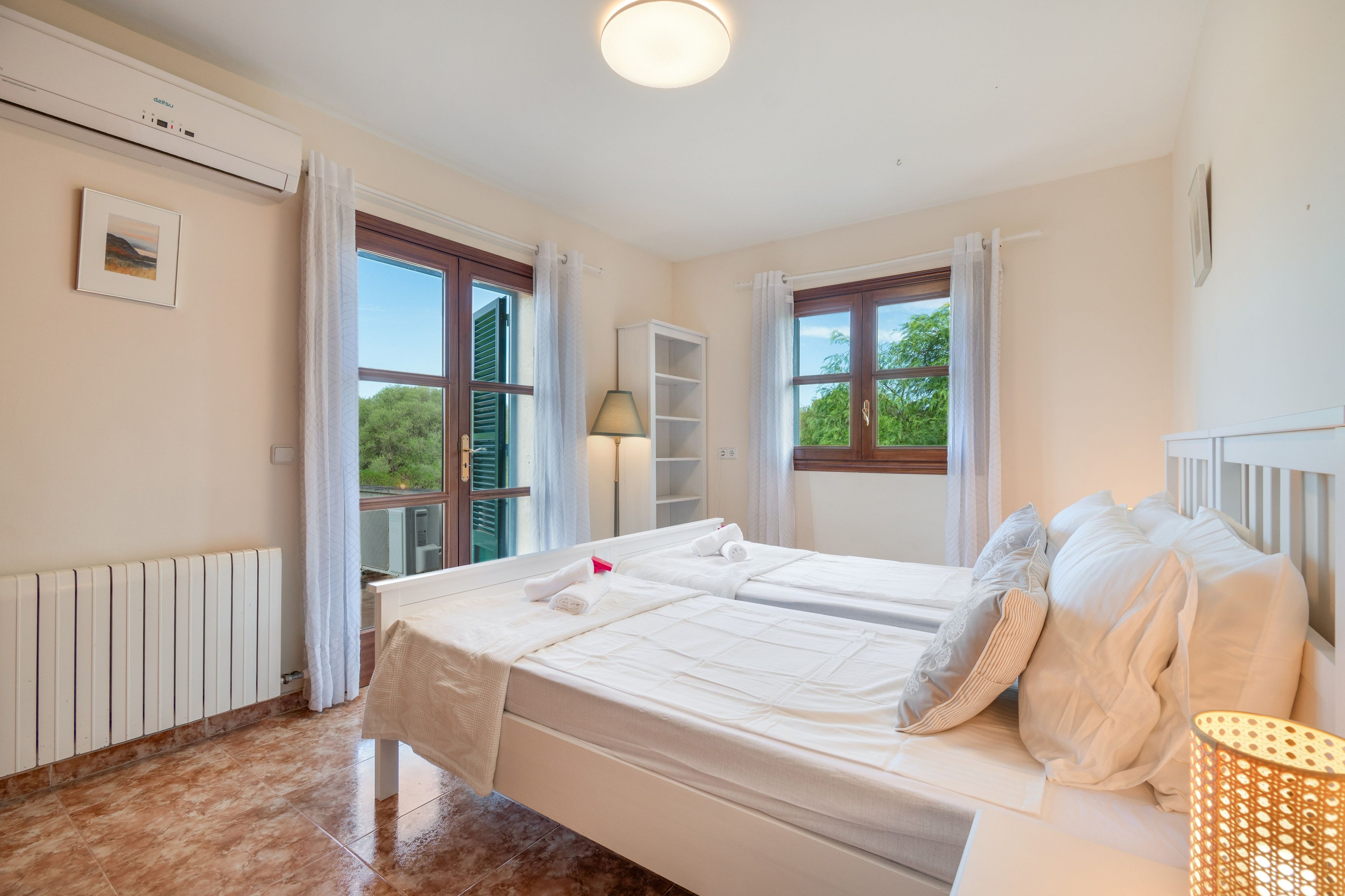Ein Hotelzimmer mit Bett, Nachttisch, Lampe und einem Fenster mit Vorhängen.