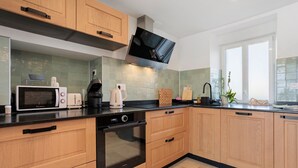 A modern kitchen with wooden cabinets, a black oven, a microwave, a toaster, and a coffee maker.