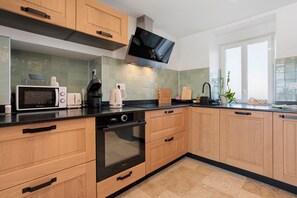 A modern kitchen with wooden cabinets, a black oven, a microwave, a toaster, and a coffee maker.