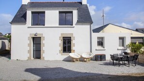 A two-story house with a gravel driveway, two front windows, and a door.