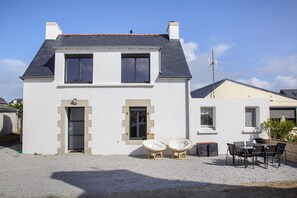 A two-story house with a gravel driveway, two front windows, and a door.