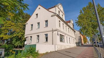Ein mehrgeschossiges Gebäude mit einer symmetrischen Fassade, großen Fenstern und einem Eckturm.