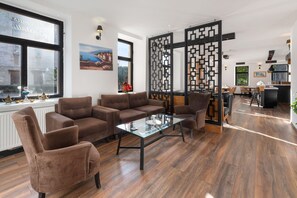 A modern living room with a brown sofa set, a glass coffee table, and a decorative partition.