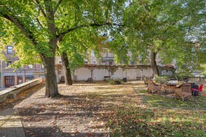Un espace extérieur aménagé avec des tables et des chaises, entouré d’arbres et d’un mur de briques.