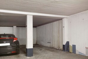 Un garaje para estacionar con un coche aparcado en un espacio señalizado con los números 26 y 27.