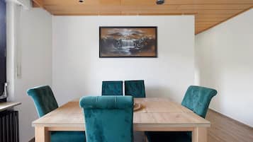 A dining area with a wooden table and four teal upholstered chairs.