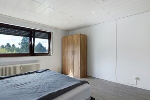 Un dormitorio con cama, armario, radiador y ventana con persianas.