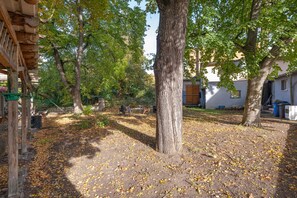 Ein Innenhof mit Bäumen, einer hölzernen Pergola und einem Gebäude im Hintergrund.