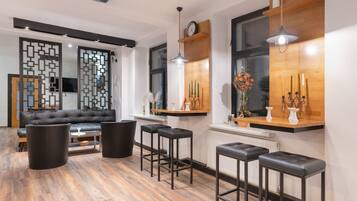 A modern living room with a black leather sofa, a coffee table, and black stools.