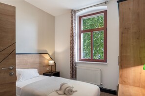 A bedroom with a bed, a nightstand, a lamp, a window with curtains, and a radiator. - Apartment 'Istanbul Single Room' with Shared Garden and Wi-Fi (Weißenfels)