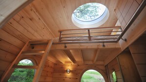 A wooden interior with a skylight, a balcony, and a window.