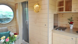 A compact kitchen with wooden cabinetry, a built-in stove, and a window with a view of the outdoors.