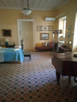 A room with a bed, a desk, a chair, a sofa, and a patterned floor. - Louisa's Cottage – Hilltop Retreat in Bochali (Zakynthos)