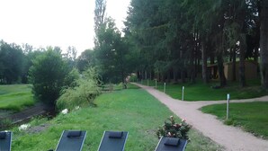 A swimming pool with lounge chairs, a dirt path, and a grassy area with trees.