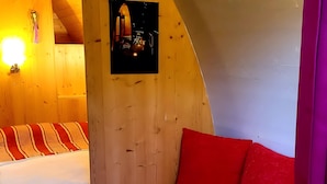 A small, cozy room with two beds, wooden walls, and a sloped ceiling.
