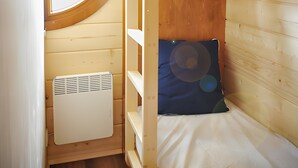A compact room with a bunk bed, a small heater, and a window with curtains.