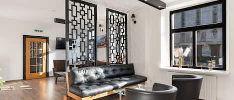 A modern waiting area with a leather sofa, black chairs, and a decorative partition.