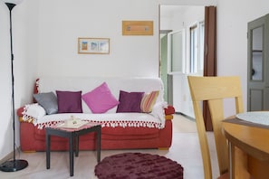 A living room with a red sofa, a small table, a chair, and a floor lamp.