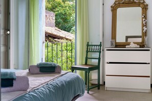 A bedroom with a bed, a chair, a dresser, and a mirror.