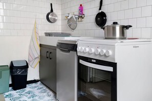 Una cocina con estufa, horno y diversos utensilios.