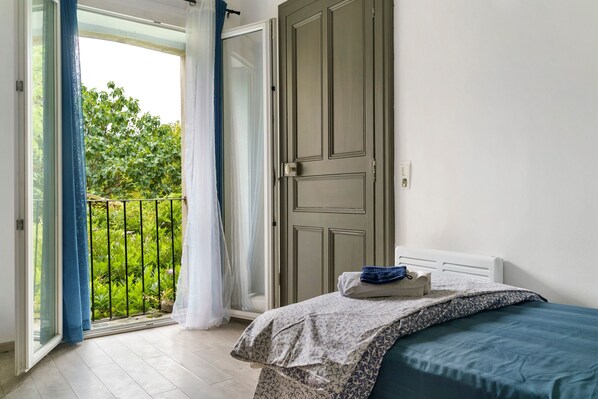 A bedroom with a bed, a door, and a view of greenery outside.