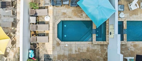 Uma área de piscina externa com espreguiçadeiras, guarda-sóis e uma pequena mesa.