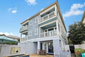A two-story building with a balcony on the upper floor and a covered patio area with a table and chairs. - Wally's World|Private Pool|Elevator|Golf Cart (Inlet Beach)
