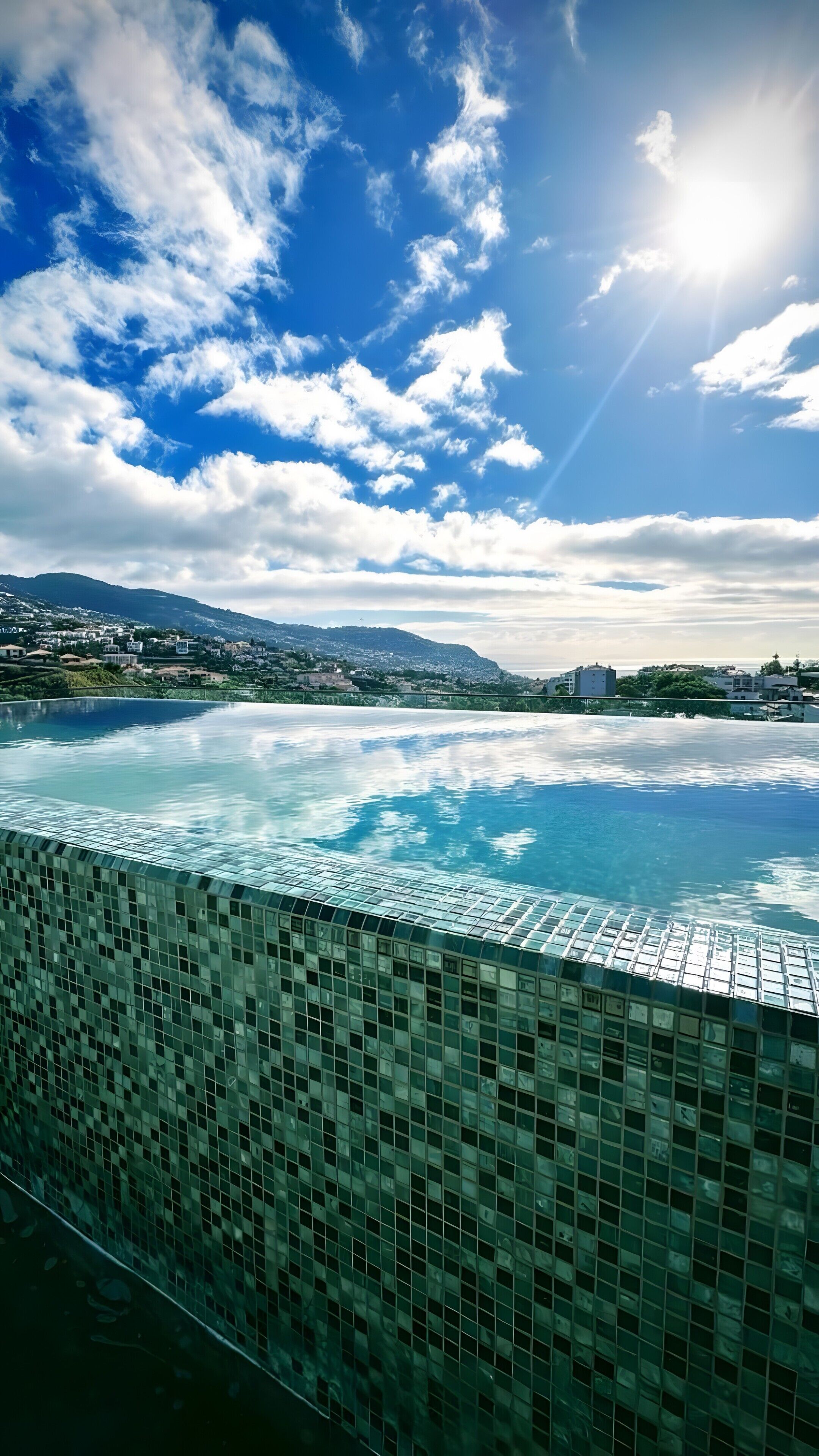 Una piscina amb vores de rajola, cel serena i muntanyes llunyanes.