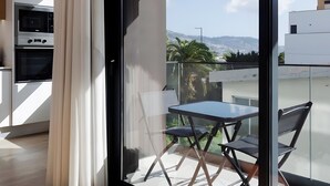 A modern interior with a sliding glass door leading to a balcony with a table and chairs.