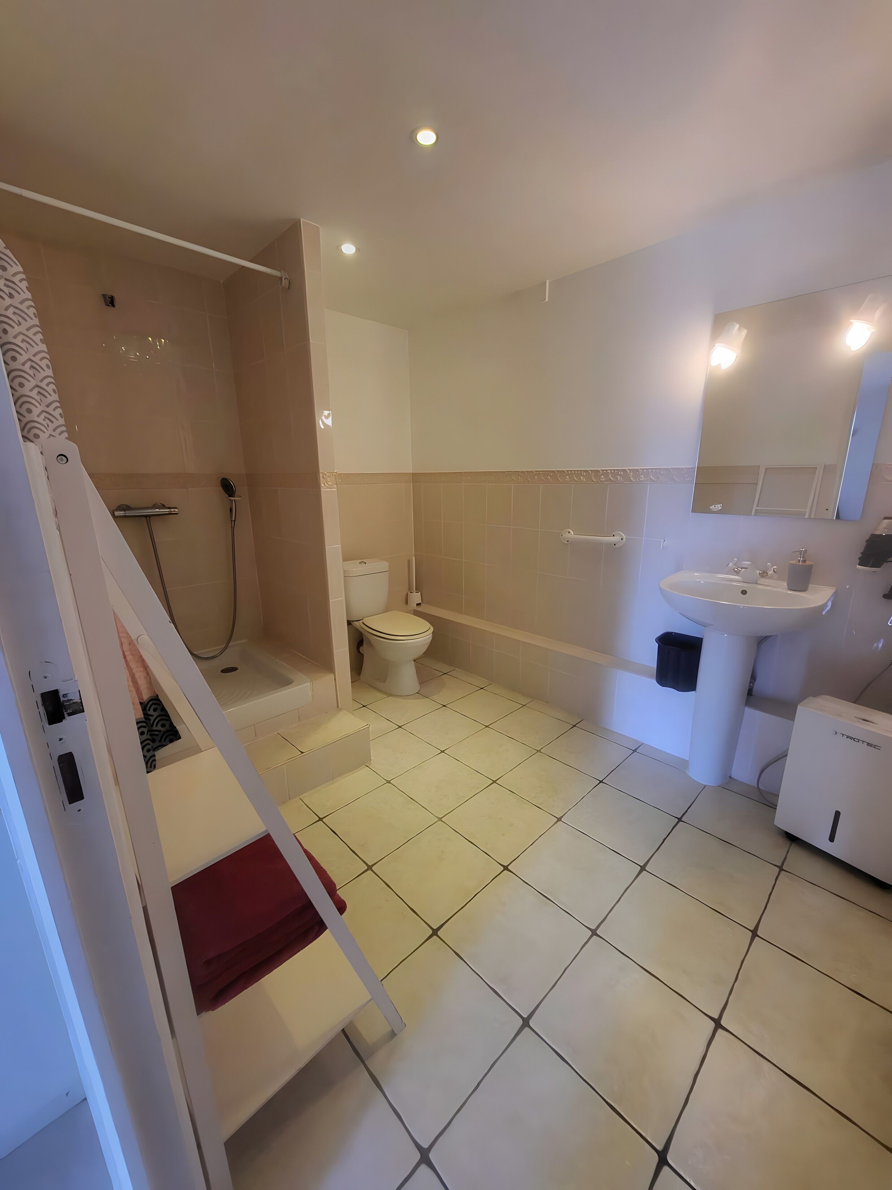 Un baño moderno con ducha, inodoro, lavabo y espejo.