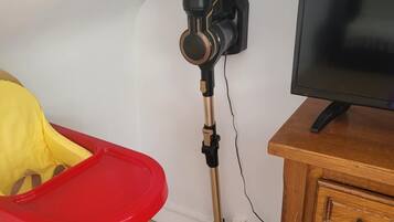 Ein Zimmer mit einem Holztisch, einem Fernseher, einem rot-gelben Hochstuhl und einer auf einem Stativ befestigten Kamera.