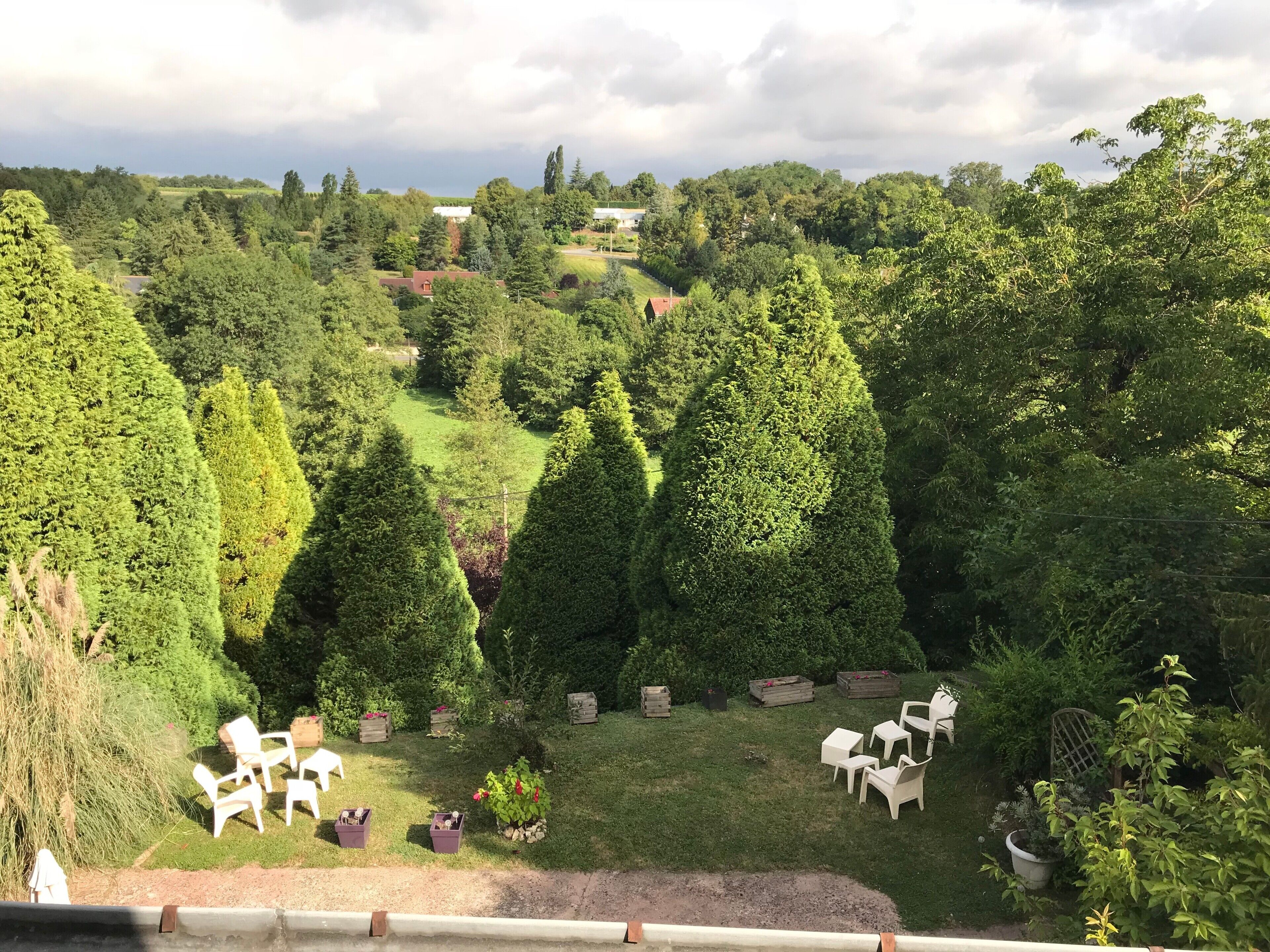 Ein üppiger Garten mit ordentlich geschnittenen Hecken, einem Rasen und Sitzgelegenheiten im Freien.